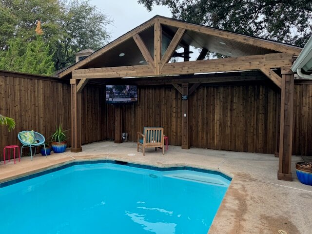 Stained wood fence with finished gazebo entertainment space with closed roof